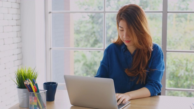 年轻美丽的亚洲女人工作与笔记本电脑在家办公，人与技术，在家里工作，在线教育视频素材