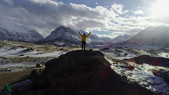 一名男性登山者在雪峰上举起手拿冰锥视频素材