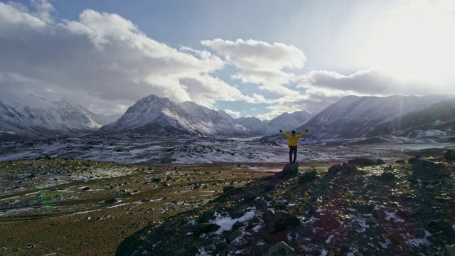 一名男性登山者在雪峰上举起手拿冰锥视频素材