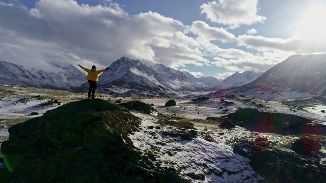 一名男性登山者在雪峰上举起手拿冰锥视频素材