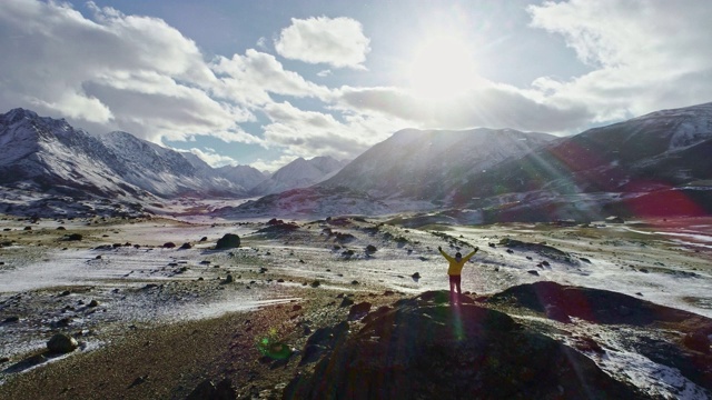 一名男性登山者在雪峰上举起手拿冰锥视频素材