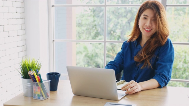 年轻美丽的亚洲女人工作与笔记本电脑在家办公，人与技术，在家里工作，在线教育视频素材