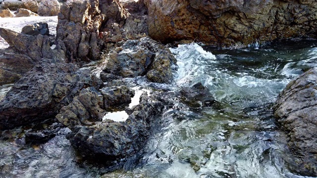 4K视频选择对焦中等拍摄清澈的海水海浪拍打岩石在夏季岛屿海滩制造许多泡沫视频素材