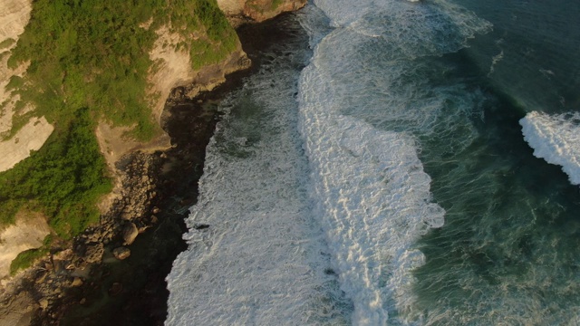 鸟瞰图美丽的悬崖和波浪在日落。无人机在海面上拍摄的画面。Uluwatu,巴厘岛视频素材