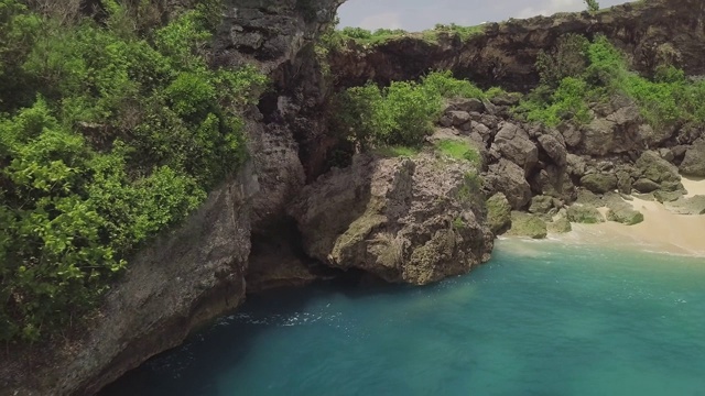 空中景观悬崖上的岩石海岸。美丽的蓝色海浪拍打着海岸上的岩石悬崖。绿松石海水和岩石岛无人机视图。印尼巴厘岛视频素材