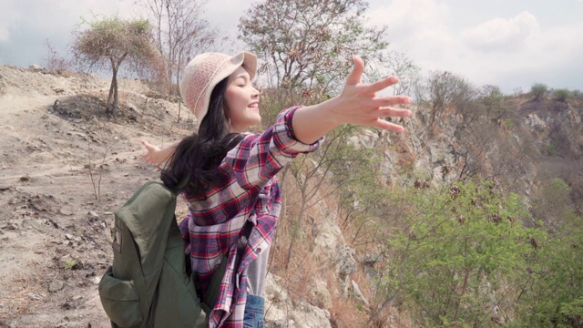 徒步旅行者亚洲背包女步行到山顶，女性享受她的假期在徒步冒险感觉自由。生活方式女性旅行和放松的自由时间概念。视频素材