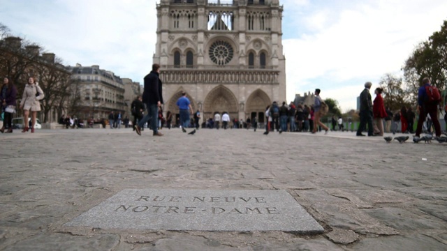 低角度的西方façade的巴黎圣母院大教堂和特写Rue Neuve Notre-Dame刻在一块石头匾上的鹅卵石街道，法国巴黎视频素材