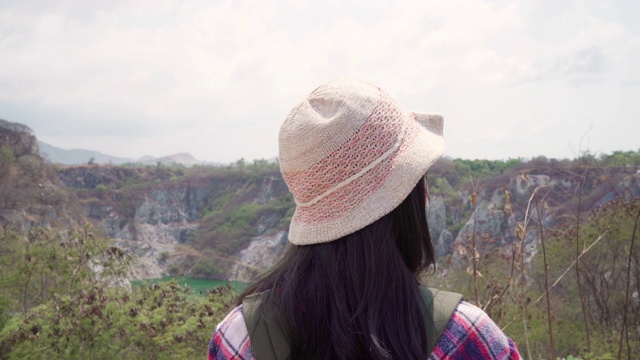 徒步旅行者亚洲背包女步行到山顶，女性享受她的假期在徒步冒险感觉自由。生活方式女性旅行和放松的自由时间概念。视频素材