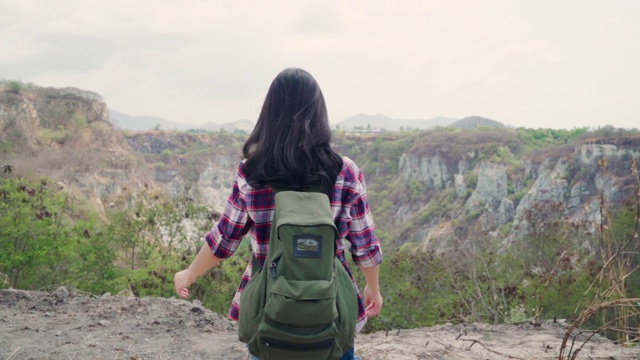 慢动作-徒步旅行者亚洲背包女步行到山顶，女性享受她的假期在徒步冒险感觉自由。生活方式女性旅行和放松的自由时间概念。视频素材