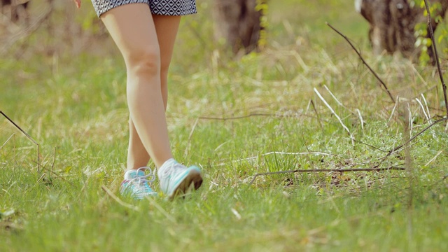 女人穿着运动鞋穿过森林里的草地。底部视图。视频素材