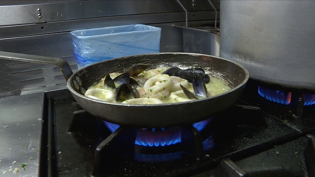 匿名厨师sautéing海鲜在餐厅厨房。视频素材