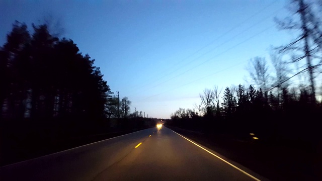 在清晨驾驶乡村道路。司机视角沿着美丽的晨曦乡村街道。视频素材