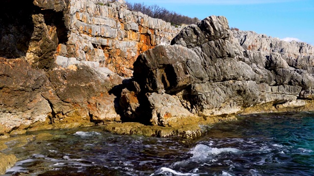 海浪与海岸岩石一起涌动。前景是未聚焦的石头视频素材