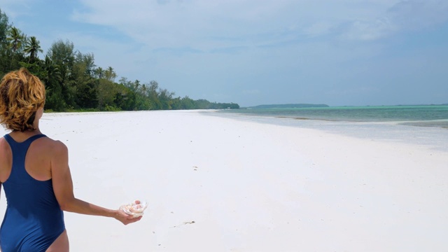 女人走在阳光明媚的热带海滩上视频素材