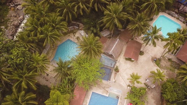 鸟瞰热带度假酒店的蓝色游泳池。无人机景观旅游酒店与室外游泳池和棕榈树的背景。视频素材