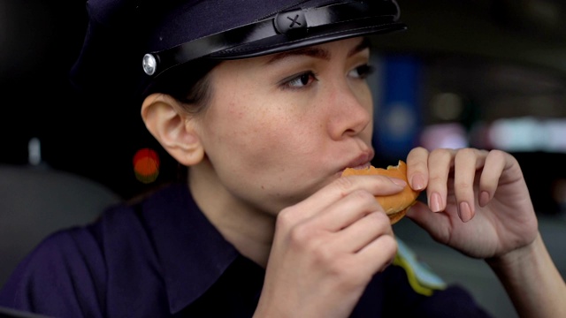 女警官坐在车里吃着早餐，吃着芝士汉堡视频素材