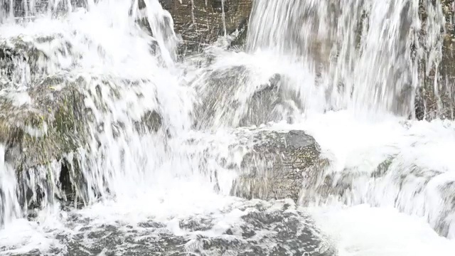 4K近距离的水流与白色透明的气泡和岩石。水背景和自然壁纸。视频素材