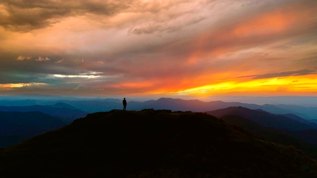 一个人站在山上，映衬着美丽的夕阳视频素材