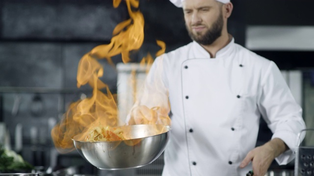 厨师在厨房用平底锅用慢动作烹饪。年轻的厨师视频素材