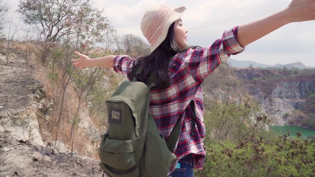 徒步旅行者亚洲背包女步行到山顶，女性享受她的假期在徒步冒险感觉自由。生活方式女性旅行和放松的自由时间概念。视频素材