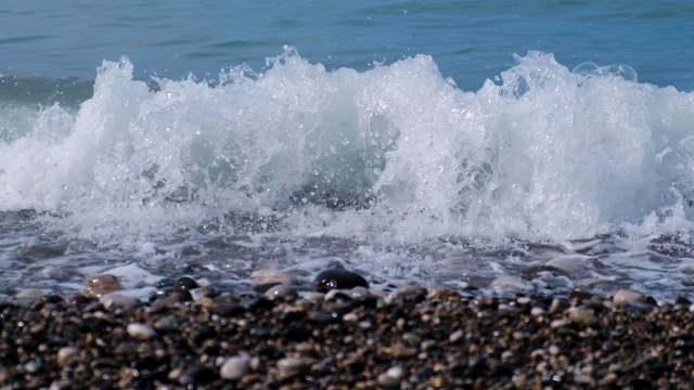 以慢动作模式拍摄视频。岩石海滩。大海的潮汐。海水的刺激。波在岸上。在海滩上放松和宁静。湛蓝的天空，蔚蓝的海水。视频素材