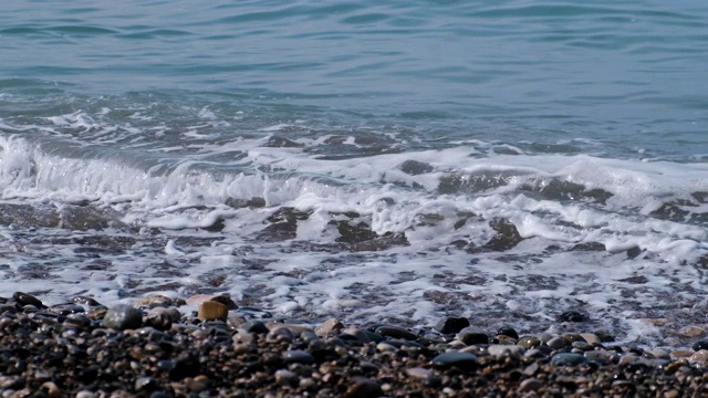 以慢动作模式拍摄视频。岩石海滩。大海的潮汐。海水的刺激。波在岸上。在海滩上放松和宁静。湛蓝的天空，蔚蓝的海水。视频素材