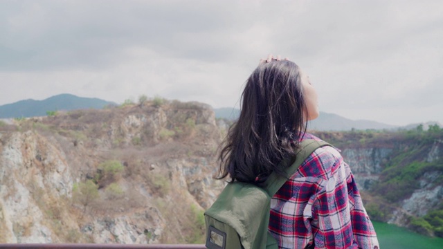 徒步旅行者亚洲背包女在山顶，女性享受她的假期徒步冒险感觉自由。生活方式女性旅行和放松的自由时间概念。视频素材