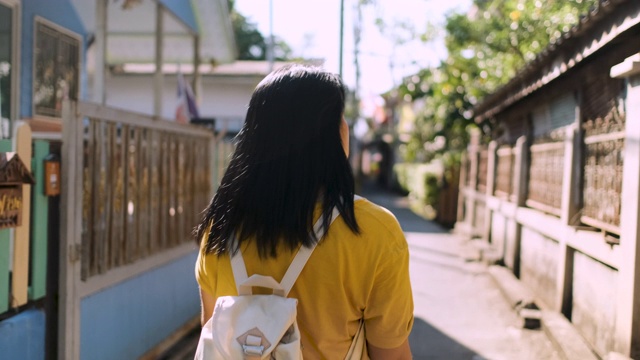 慢镜头亚洲女人在阳光明媚的日子里在城市的小巷里散步和观光视频素材