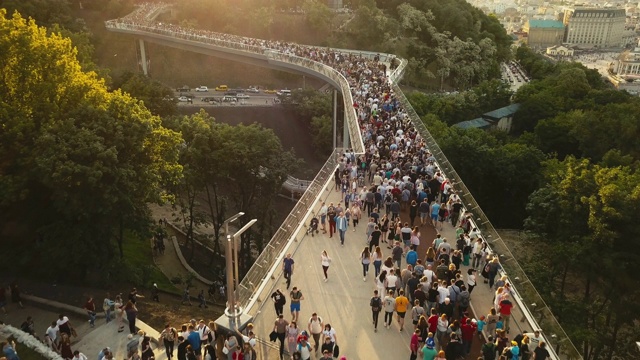 春天的傍晚，一群人在人行天桥上。鸟瞰图。在乌克兰首都基辅市中心，一座新的自行车步行桥。为游客远足和步行视频素材