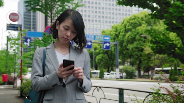 日本女商人在路上使用智能手机视频素材