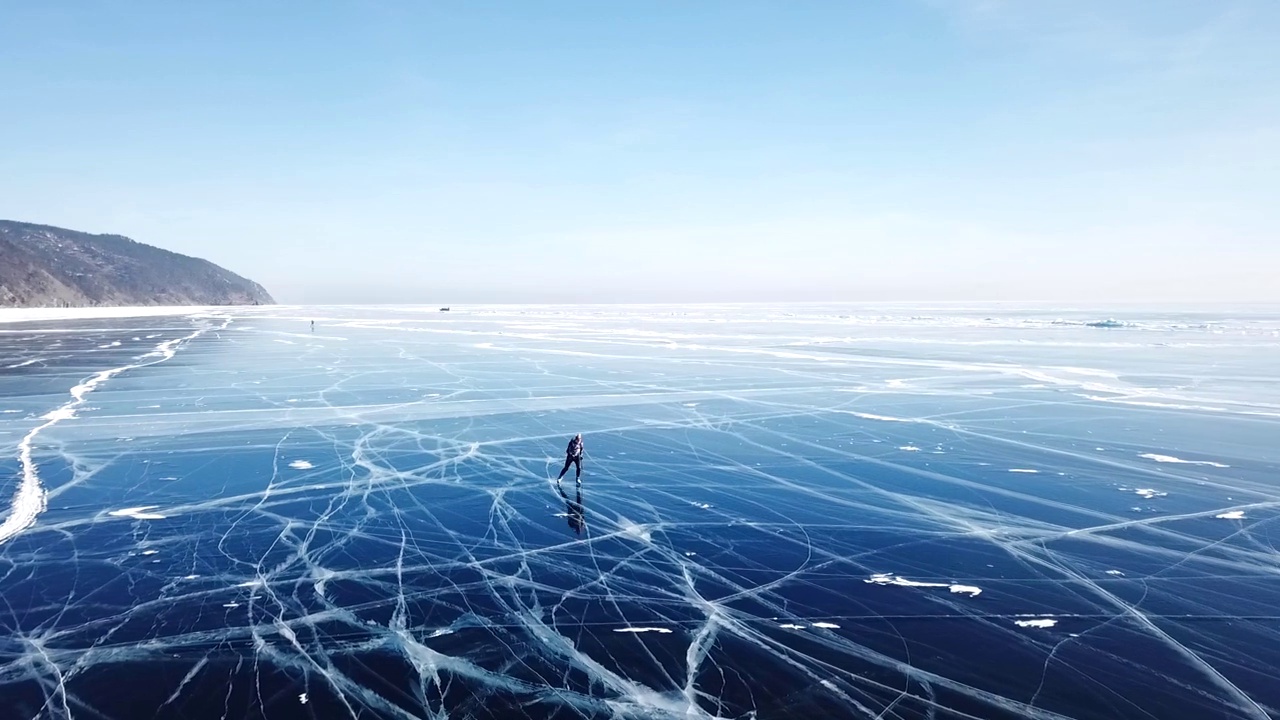 游客们走在光滑的表面上。风景如画的贝加尔湖裂缝，蓝色，光滑，透明的冰丘，雪堆。亚洲最好的北俄罗斯。冬天阳光明媚，天蓝蓝的。天线的方法。视频素材