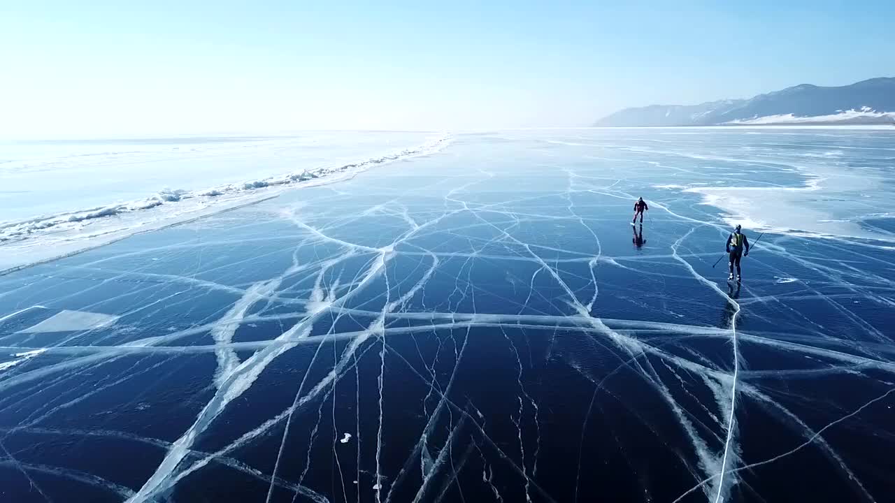 游客们走在平坦的地面上。风景如画的贝加尔湖，蓝色、光滑、清澈的冰丘、雪堆。最好的北俄罗斯亚洲。冬天晴天蓝天。天线的方法。视频素材