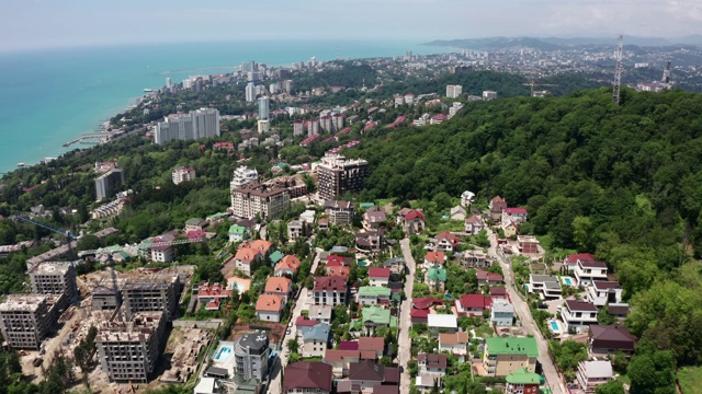 航拍视频拍摄。从索契城的高处俯瞰全景。绿树青山傍海。住宅区域。海滩上的高房子。蔚蓝晴朗的天空。视频素材