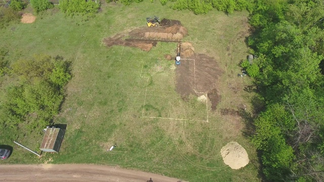 新建房屋用小型装载机和挖掘机开挖基坑的架空视频素材