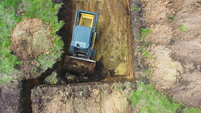 小型装载机在草坪上自顶向下挖土，用于新建房屋基坑视频素材