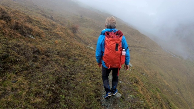 成熟的徒步旅行者走在郁郁寡欢的山路上视频素材