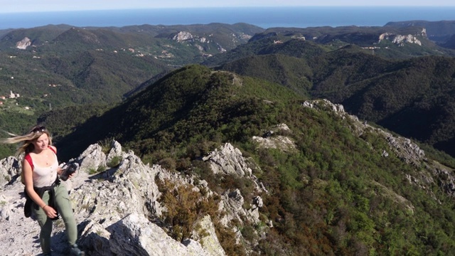 女性徒步者攀登岩石山脊以上的山脉，大海视频素材