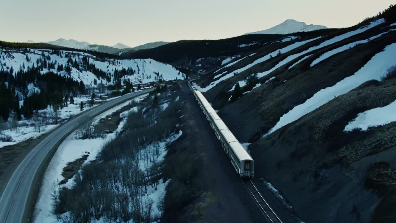 在雪山中，无人机在客运列车后面飞行视频素材