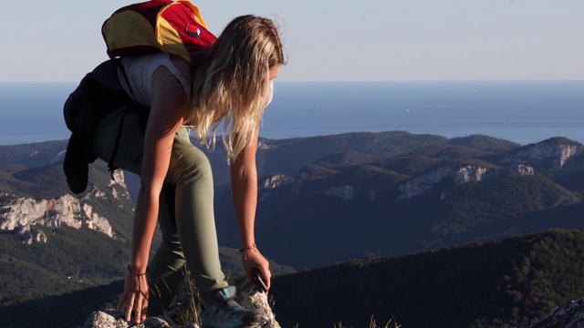 女性徒步旅行者攀登山脉之上的山脊视频素材