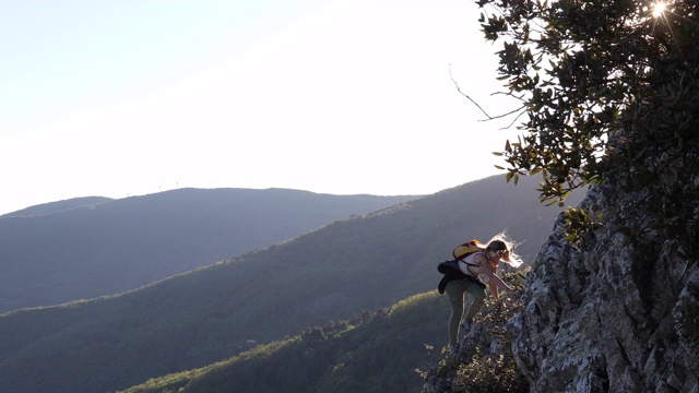 女性徒步旅行者攀登山脉之上的山脊视频素材