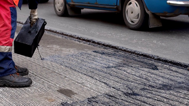 道路维修。工作细节上，工人们将树脂浇筑路面以覆盖沥青。视频素材