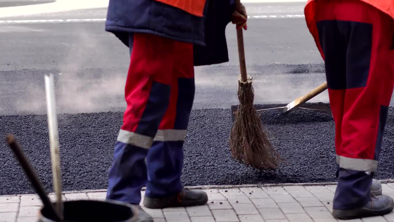 在城市街道上涂沥青和修理的压路工和工人。特写镜头。视频素材