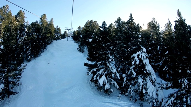 滑雪缆车通过松林地区的日出，到冬季滑雪场的山坡上，POV拍摄视频素材