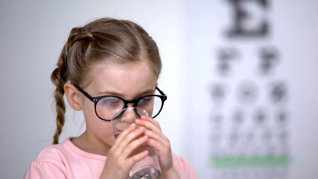 美丽的小女孩戴着眼镜，喝着药片进行视力治疗，补充视频素材