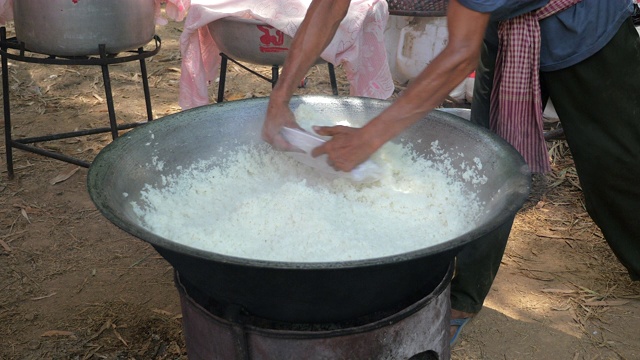 一名男子从大锅里拿出炒饭，放在一个金属盆里(靠近)视频素材