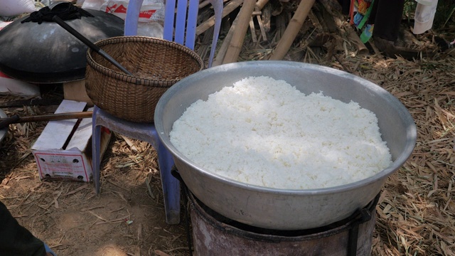 一名男子从大锅里拿出炒饭，放在一个金属盆里(靠近)视频素材