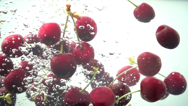 甜樱桃落在水中。缓慢的运动。视频素材