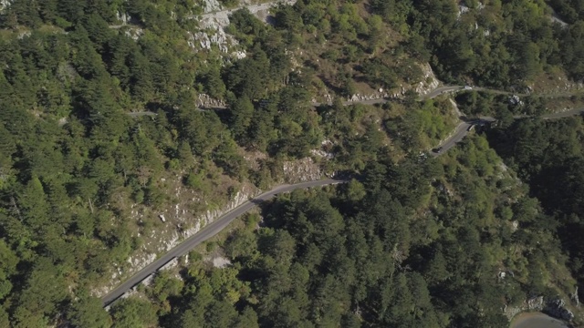 鸟瞰图山形蜿蜒的道路与卡车和汽车。股票。道路交通蜿蜒在高山狭窄的角落，汽车变成绿色的森林视频素材