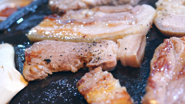 在韩国餐厅里煎煮黑猪肉饭，新鲜美味的韩国菜菜肴在铁板上配上生菜，拉近距离，复制空间，生活方式视频素材