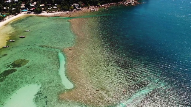 岛岸附近的船只。传统的彩色渔船漂浮在平静的蓝色水域附近的白色沙滩上的热带异国天堂岛。透过绿色的棕榈叶。帕视频素材